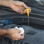Driver checking engine oil level using the dipstick.